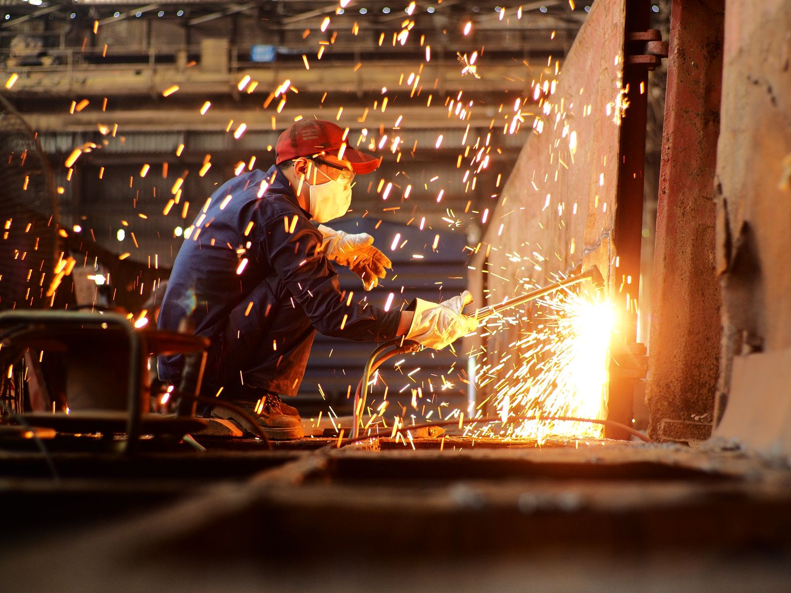 Welder working in a factory, sparks flying — a high-temperature working environment