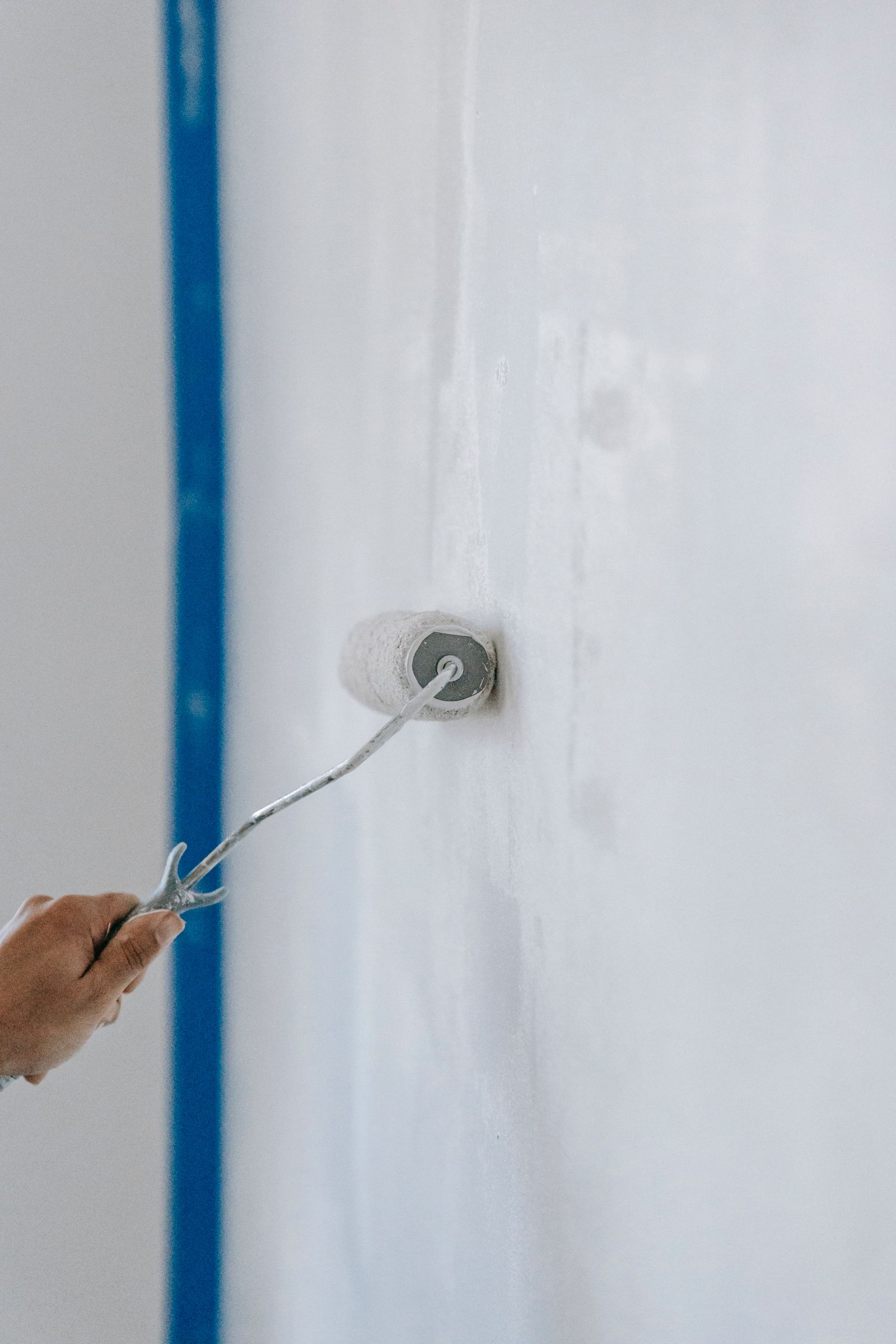 Cận cảnh người dùng con lăn sơn tường màu trắng